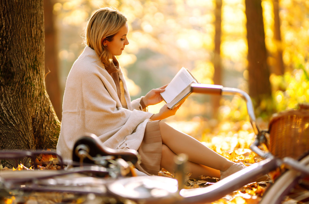 September holidays pic. Woman reading book under tree